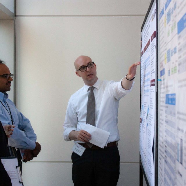 Photo of a professor pointing to a poster